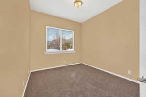 Spare room featuring dark carpet and baseboards