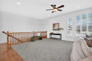 Living area with an upstairs landing, ceiling fan, recessed lighting, and wood-type flooring