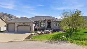 French country style house featuring a front lawn, a garage, driveway, brick siding, and a mountain view