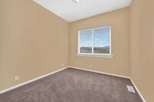 Unfurnished room featuring dark colored carpet and baseboards