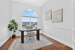 Office with dark wood-type flooring and ornamental molding