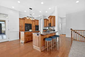 Kitchen featuring dark stone countertops, a center island, wood finish cabinetry, and light wood-style flooring