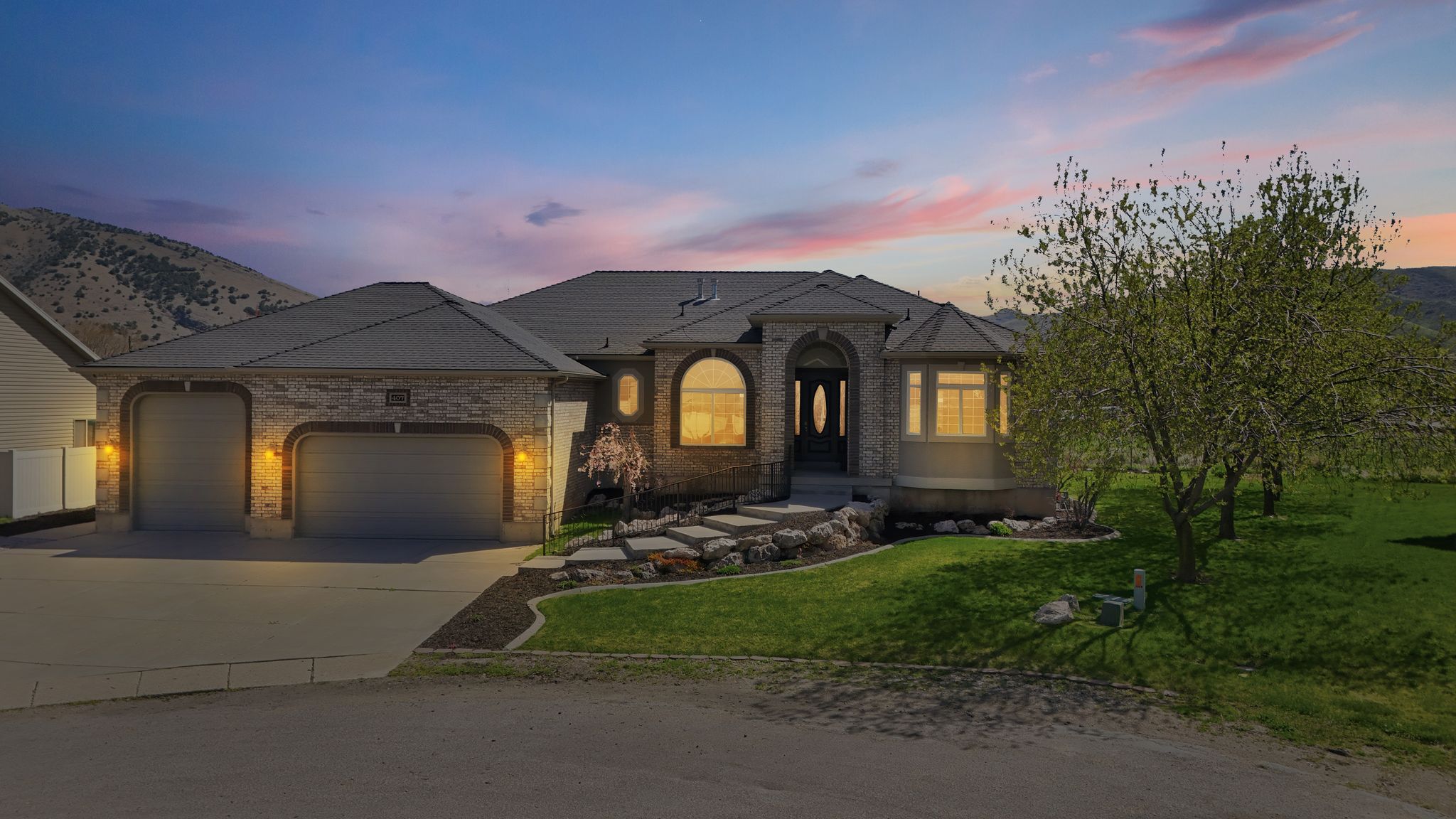 French country inspired facade featuring a yard, a garage, driveway, and brick siding