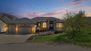 French country inspired facade featuring a yard, a garage, driveway, and brick siding