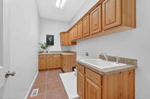 Laundry area featuring hookup for a washing machine, cabinet space, and light tile patterned flooring