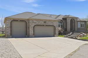 French provincial home featuring a garage, concrete driveway, a shingled roof, and brick siding