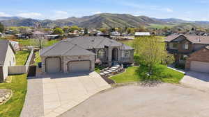 French country inspired facade with an attached garage, concrete driveway, a residential view, and a mountain view