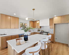 Kitchen with light wood finished floors, backsplash, a breakfast bar, and a kitchen island