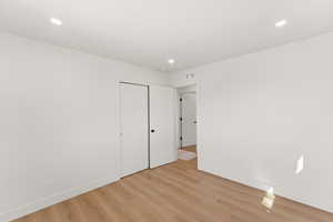 Unfurnished bedroom with light wood finished floors, a closet, and recessed lighting