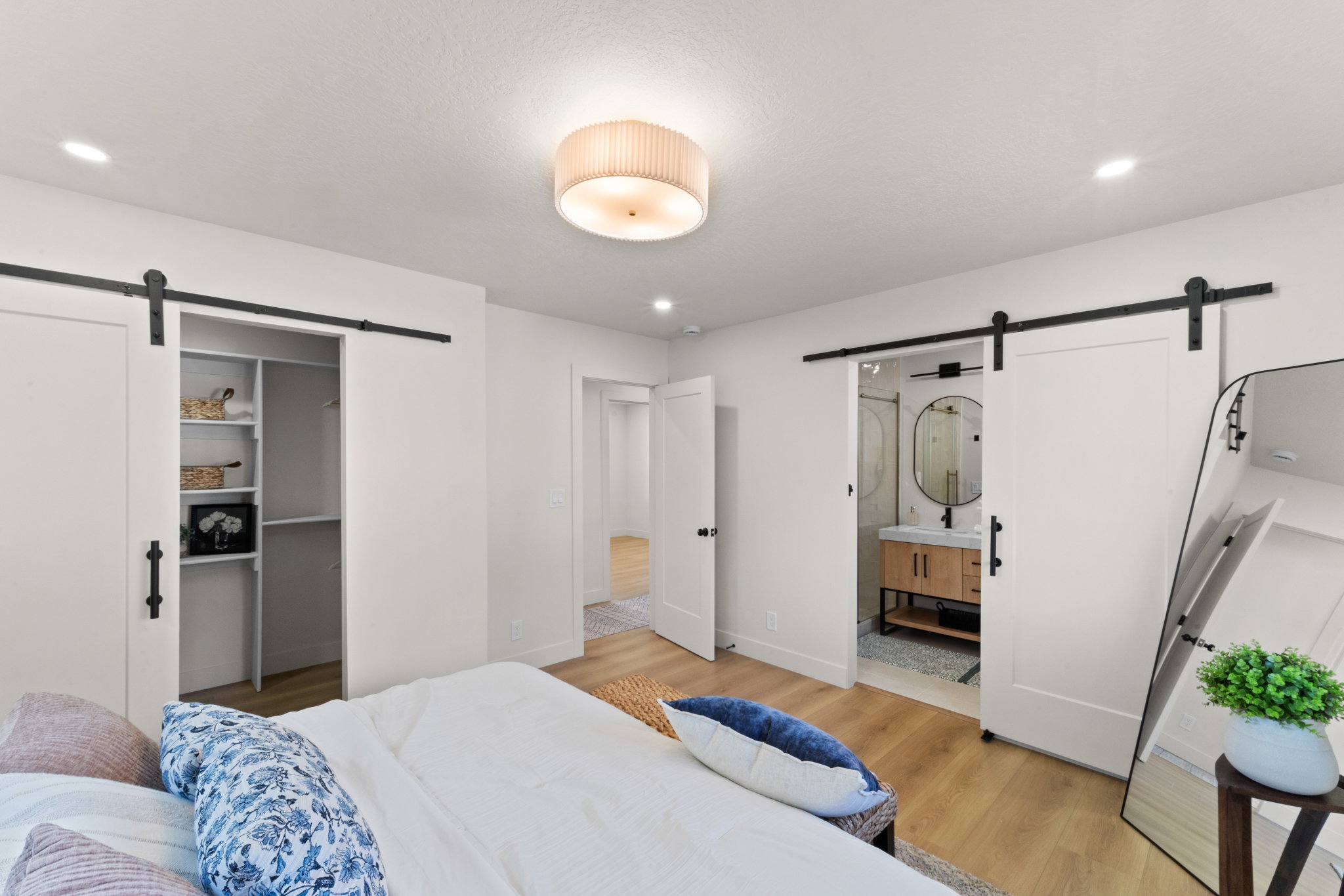Bedroom featuring a barn door, a spacious closet, light wood-style floors, ensuite bathroom, and recessed lighting