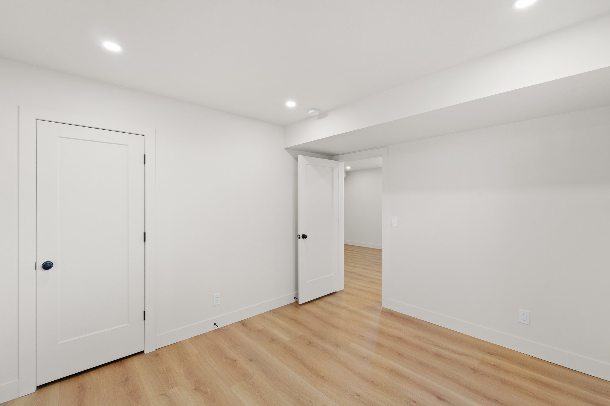 Finished basement with light wood finished floors and recessed lighting