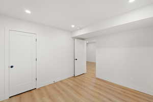 Finished basement with light wood finished floors and recessed lighting