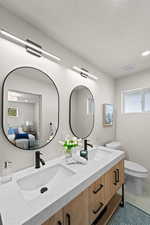 Full bathroom featuring plenty of natural light, ensuite bath, double vanity, light tile patterned floors, and a textured ceiling