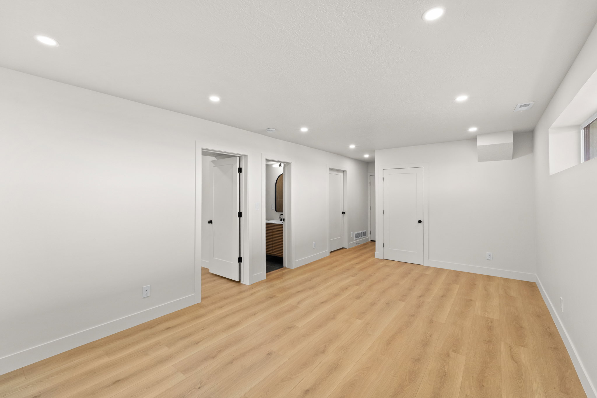 Below grade area with light wood-type flooring and recessed lighting