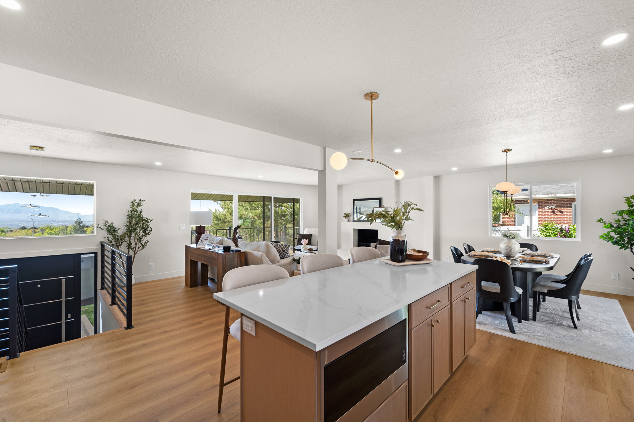 Kitchen featuring a breakfast bar area, light stone counters, light wood finished floors, stainless steel microwave, and a textured ceiling