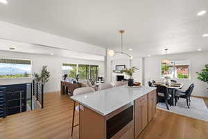 Kitchen featuring a breakfast bar area, light stone counters, light wood finished floors, stainless steel microwave, and a textured ceiling