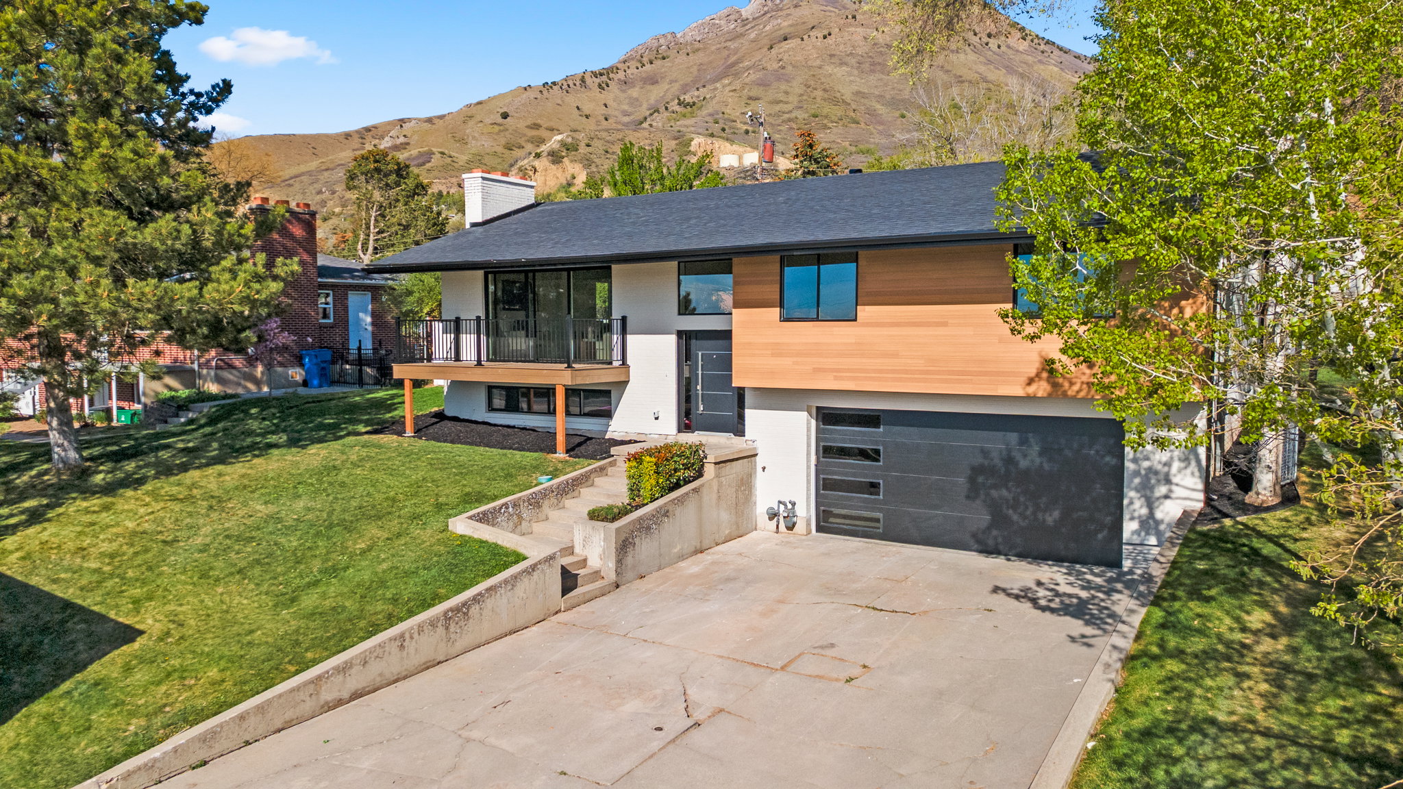 View of front of property with driveway, a front lawn, a balcony, a chimney, and an attached garage