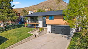 View of front of property with driveway, a front lawn, a balcony, a chimney, and an attached garage