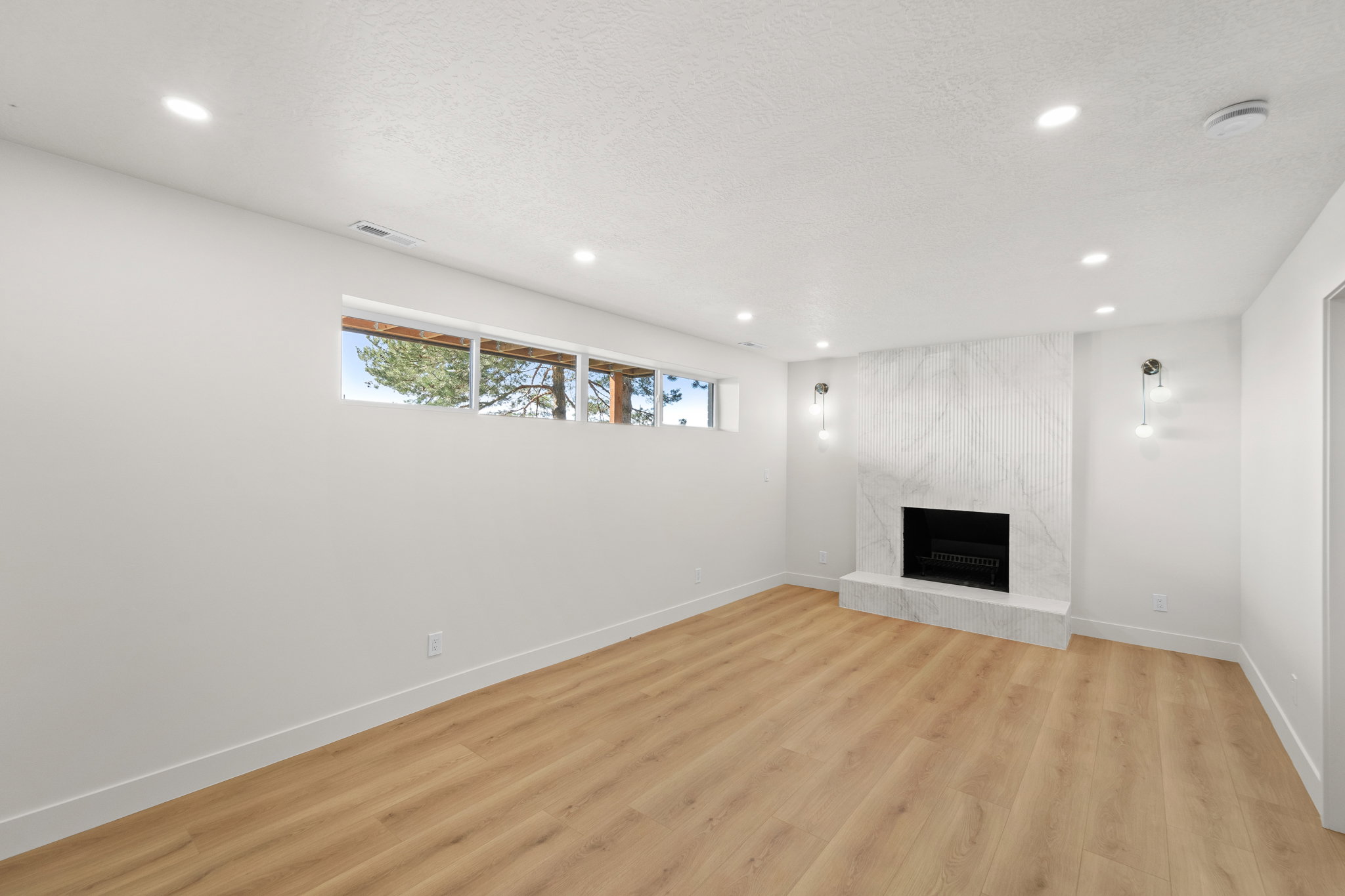 Unfurnished living room featuring a premium fireplace, light wood-style flooring, recessed lighting, and a textured ceiling