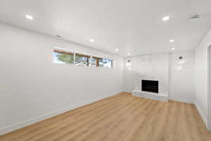 Unfurnished living room featuring a premium fireplace, light wood-style flooring, recessed lighting, and a textured ceiling