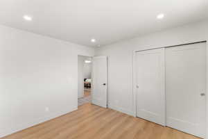Unfurnished bedroom with light wood-type flooring, a closet, and recessed lighting