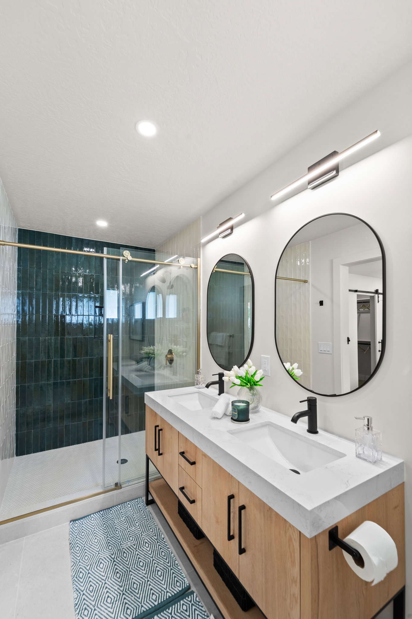 Bathroom featuring double vanity, a shower stall, and light tile patterned flooring