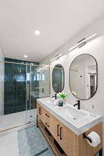 Bathroom featuring double vanity, a shower stall, and light tile patterned flooring