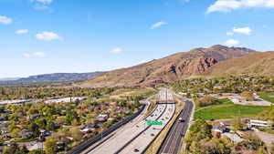 Aerial view of residential area featuring a mountain backdrop and a highway