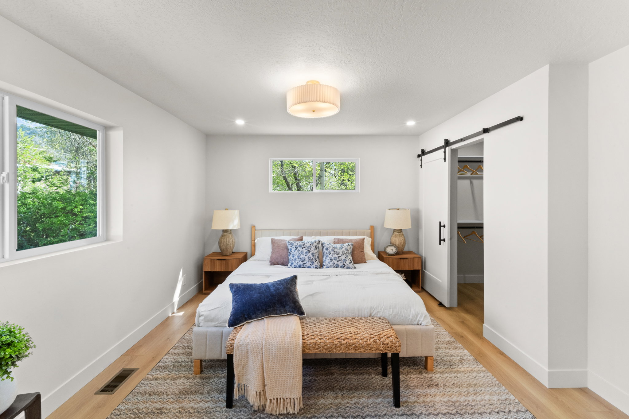 Bedroom featuring a spacious closet, a barn door, light wood-type flooring, recessed lighting, and a textured ceiling