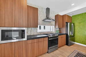 Kitchen with dark countertops, stainless steel appliances, modern cabinets, backsplash, and recessed lighting