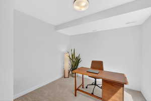 Office space with light colored carpet and baseboards