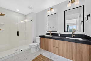 Full bath with double vanity, a shower stall, light marble finish flooring, and recessed lighting