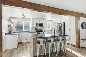 Kitchen featuring stainless steel appliances, dark stone countertops, light wood-style floors, white cabinets, and recessed lighting
