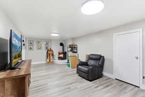 Sitting room with light wood-type flooring and a wood stove