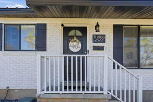 Property entrance with a porch and brick siding
