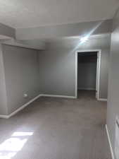 Basement Bedroom 2 Finished below grade area featuring light carpet and a textured ceiling