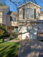 View of front of home with a garage, concrete driveway, brick siding, and a front yard