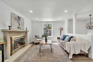 Living room featuring a high end fireplace, light wood finished floors, and hanging lights