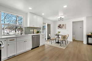 Kitchen featuring backsplash, stainless steel dishwasher, light wood-style flooring, white cabinetry, and recessed lighting