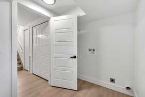 Laundry area with hookup for a washing machine and light wood-style flooring