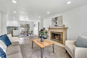 Living room with a high end fireplace, wood finished floors, and recessed lighting