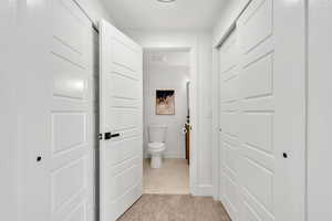 Corridor featuring light carpet and light tile patterned flooring