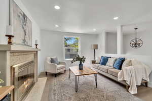 Living area with light wood finished floors, a high end fireplace, and a chandelier