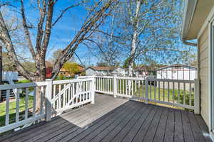 Wooden terrace featuring a residential view, a lawn, and a storage unit