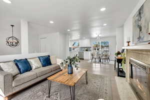 Living room featuring suspended lighting, a fireplace with flush hearth, and light wood-style floors