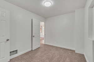 Unfurnished bedroom with light colored carpet and baseboards