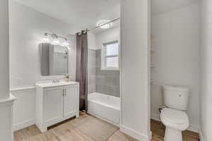 Bathroom featuring vanity, light wood-style floors, shower / bath combo with shower curtain, and a textured wall