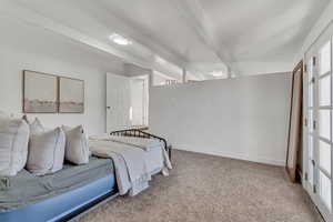 Carpeted bedroom featuring beam ceiling and baseboards