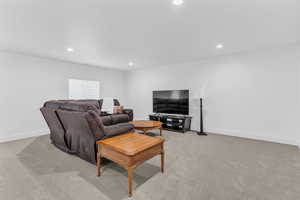 Living area with light carpet and recessed lighting