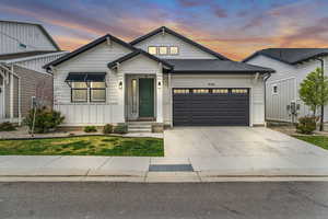 View of front of home featuring concrete driveway, a garage, and a shingled roof